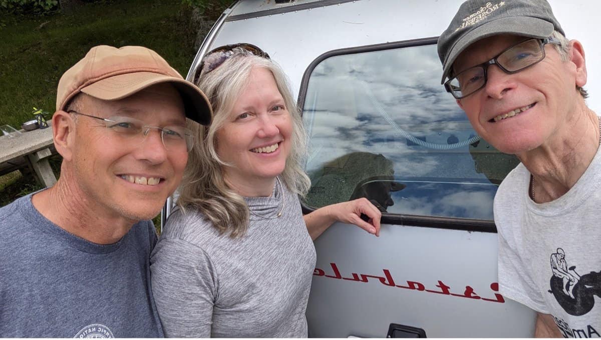 Three People Posing In Front Of A Trailer